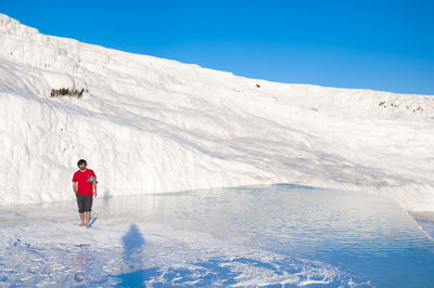 Full length of man by snowcapped mountain against clear blue sky