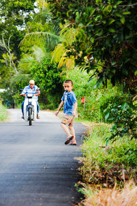 Rear view of children on bicycle against trees