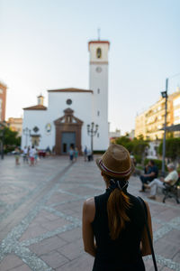 Rear view of woman standing on street against buildings