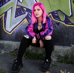 Portrait of young woman sitting on wall