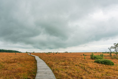 Footpath amidst field against sky