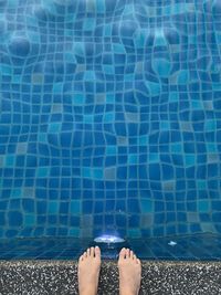 Low section of woman standing by swimming pool