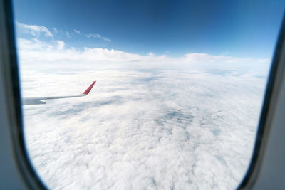 Airplane flying over glass window against sky