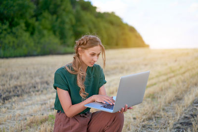 Young woman using mobile phone on field