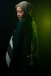 Rear view of woman standing against black background