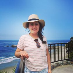 Portrait of smiling young woman standing against beach