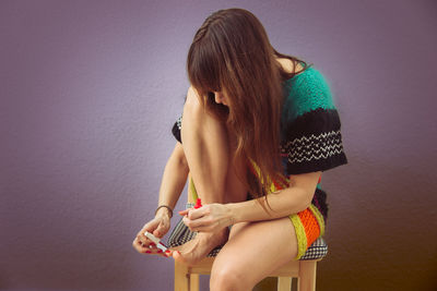 Young woman sitting against wall