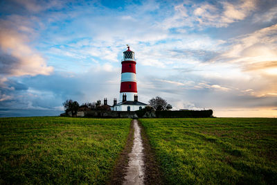 Lighthouse on field against sky