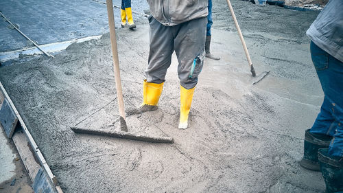 Construction worker uses bullfloat to spread cement mortar screed. cast-in-place concrete works