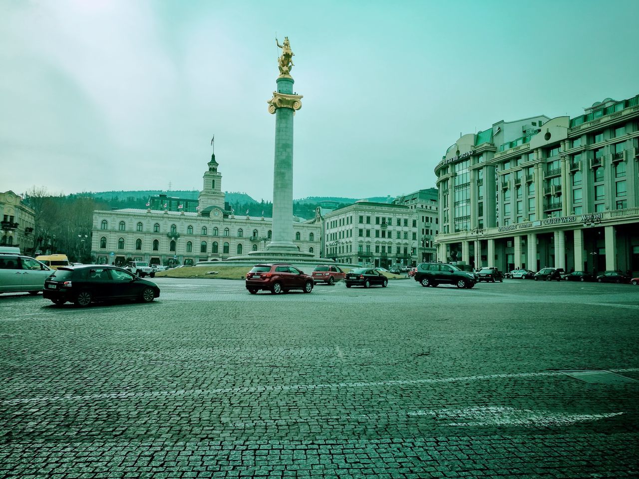 travel destinations, sky, transportation, architecture, car, city, building exterior, mode of transport, built structure, travel, land vehicle, tower, outdoors, cloud - sky, road, no people, nautical vessel, water, day, clock tower, clock, statue