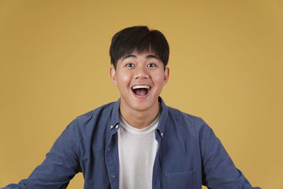 Portrait of smiling man against yellow background