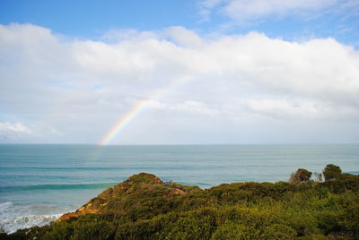 Scenic view of rainbow over sea against sky