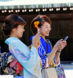 Smiling young woman using mobile phone in city