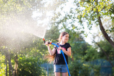 Girl spraying water with hose in yard