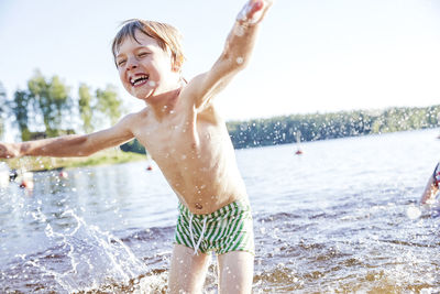 Full length of shirtless boy splashing water