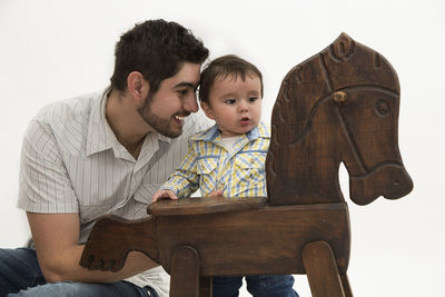 Father and son sitting on chair against white background