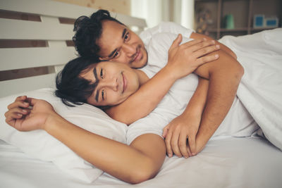 Loving gay couple lying on bed at home