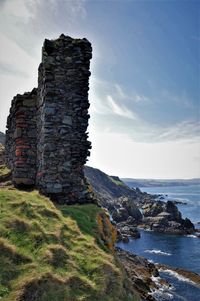 Stone wall by sea against sky