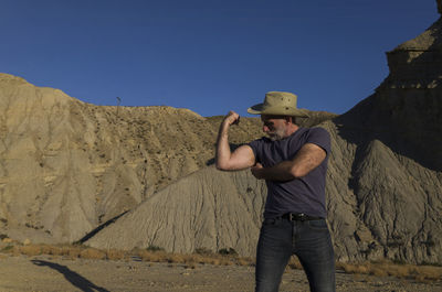 Adult man in cowboy hat on desert against mountain. almeria, spain