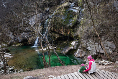 Woman sitting on rock by river