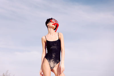 Young woman standing against sky