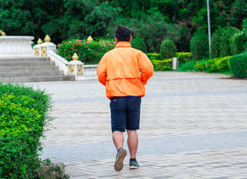 Rear view of man walking on footpath