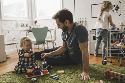 Father and daughters playing with toys in playroom at home