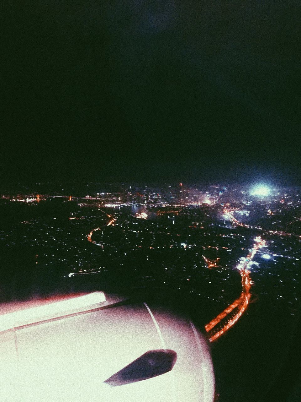 AERIAL VIEW OF ILLUMINATED CITYSCAPE AGAINST SKY AT NIGHT