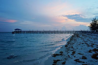 Pier over sea against sky during sunset