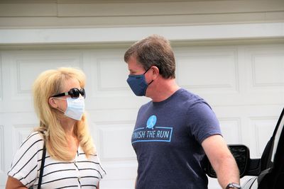 Portrait of young couple wearing masks  standing  by car