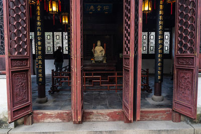 Rear view of man standing by statue in temple