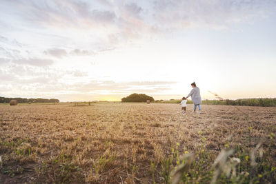 Man standing on field against sky during sunset