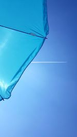 Beach - view from below on a blue sun umbrella with blue sky background and a plain