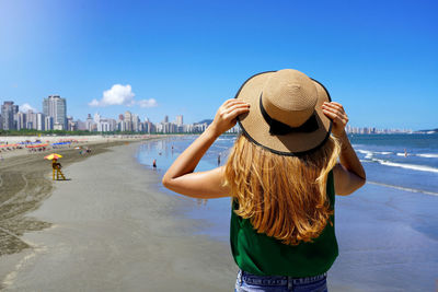 Back view of attractive woman wearing hat ready for summer vacation on the beach