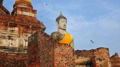 Low angle view of historic statue against building and sky