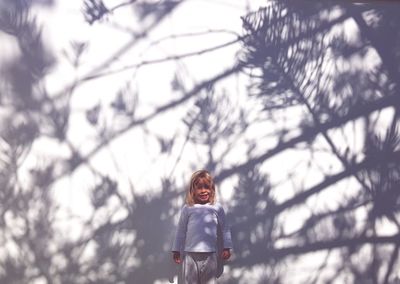 Portrait of cute girl standing against wall