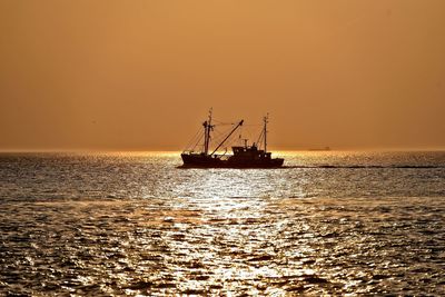 Silhouette boat in sea against clear sky during sunset