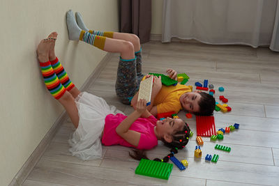 A happy boy and a little girl, lie on the floor, play with a multicolored construction