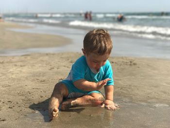 Messy boy sitting at sandy beach