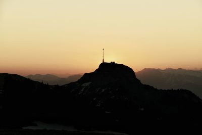 Silhouette cross on mountain against clear sky during sunset