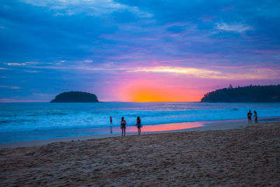 People on beach against sky during sunset