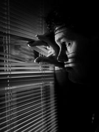 Side view of man looking through window