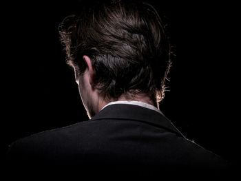 Rear view of man against black background