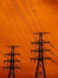 Low angle view of silhouette electricity pylon against romantic sky