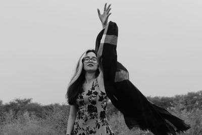 Woman throwing scarf on field against clear sky