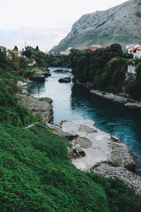 Scenic view of river by mountains against sky