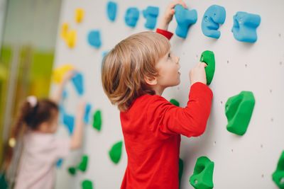 Cute boy standing against multi colored wall