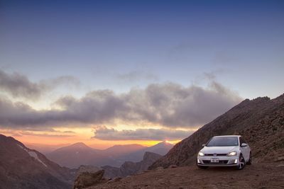 Car on mountain against sky during sunset