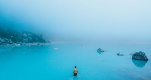 Rear view of man standing in sea against sky