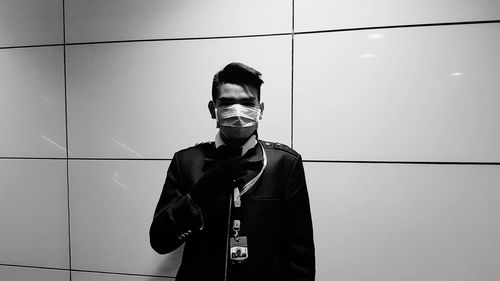 Portrait of young man standing against wall